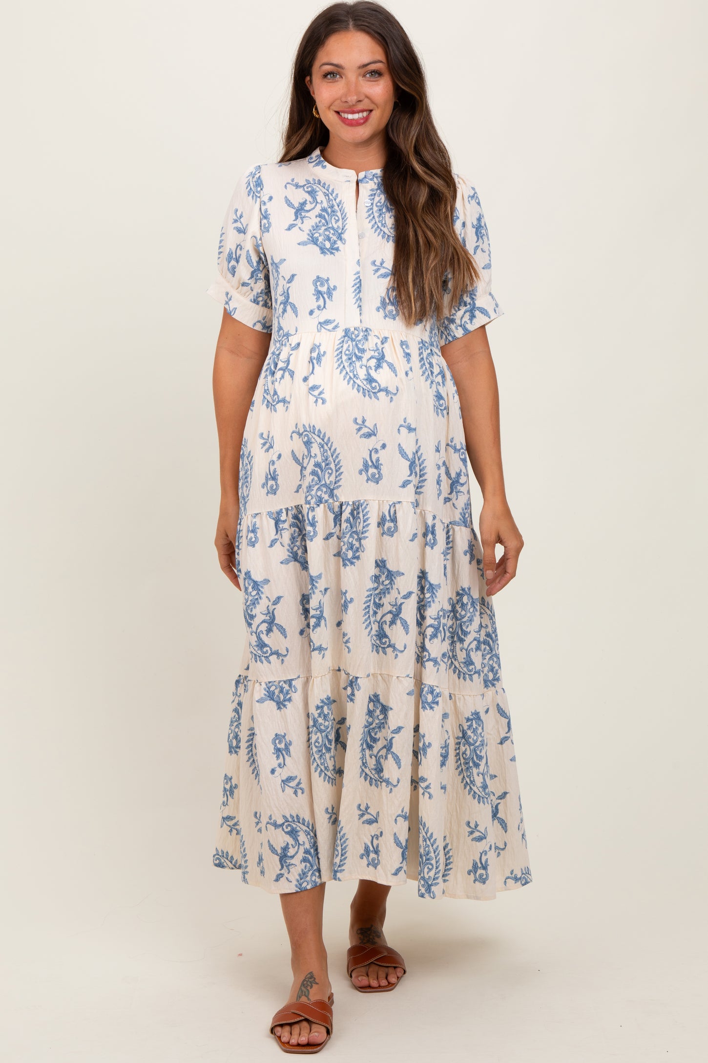 woman wearing a white and blue floral print maternity dress with tiered skirt and short sleeves