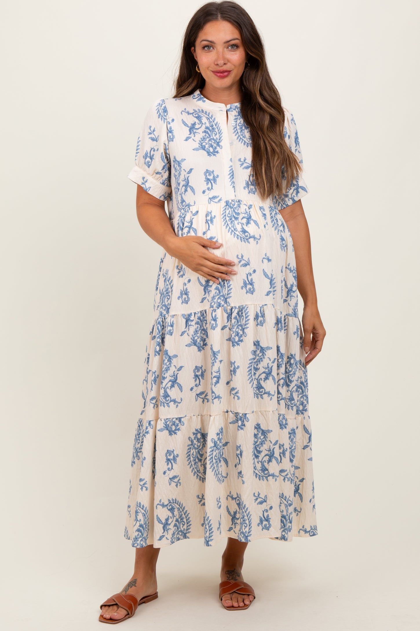 woman wearing a cream and blue floral print maternity maxi dress with a button front and baby bump visible