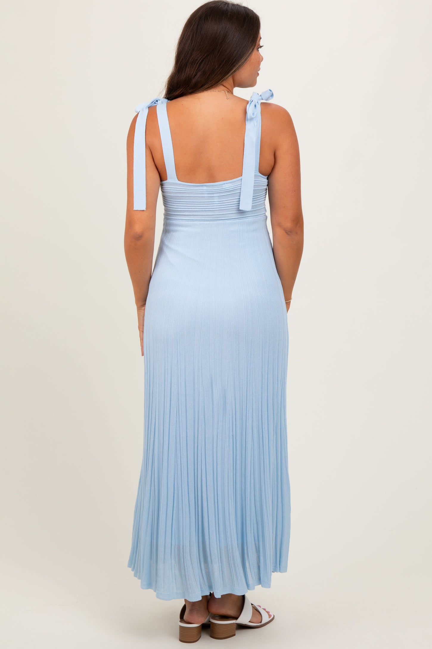 woman wearing a light blue maternity maxi dress with adjustable tie straps and a pleated skirt