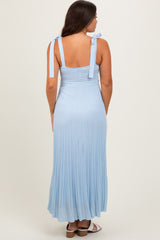 woman wearing a light blue maternity maxi dress with adjustable tie straps and a pleated skirt