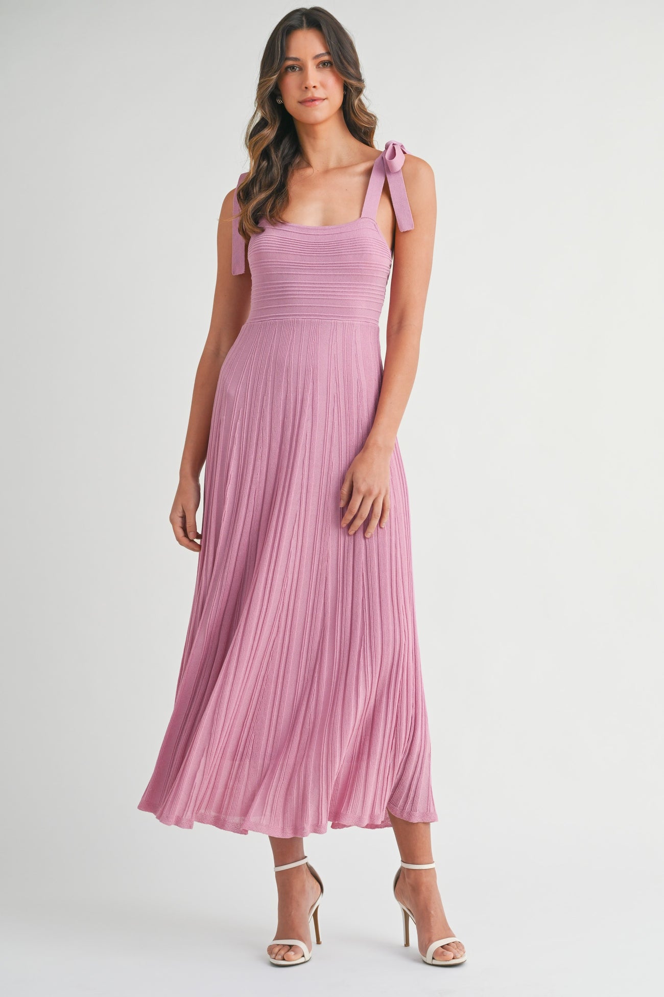 woman wearing a pink pleated maxi dress with adjustable tie straps