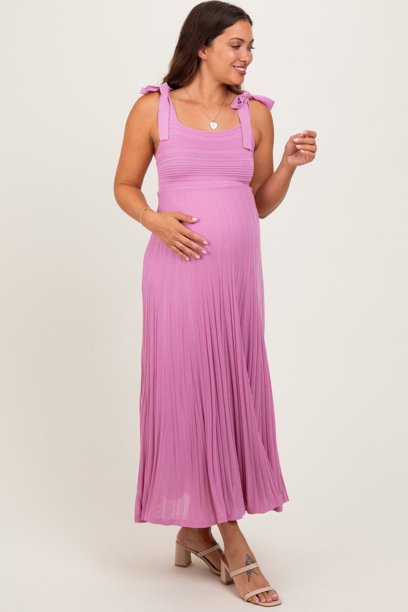 woman wearing a pink maxi maternity dress with tie straps and a visible baby bump
