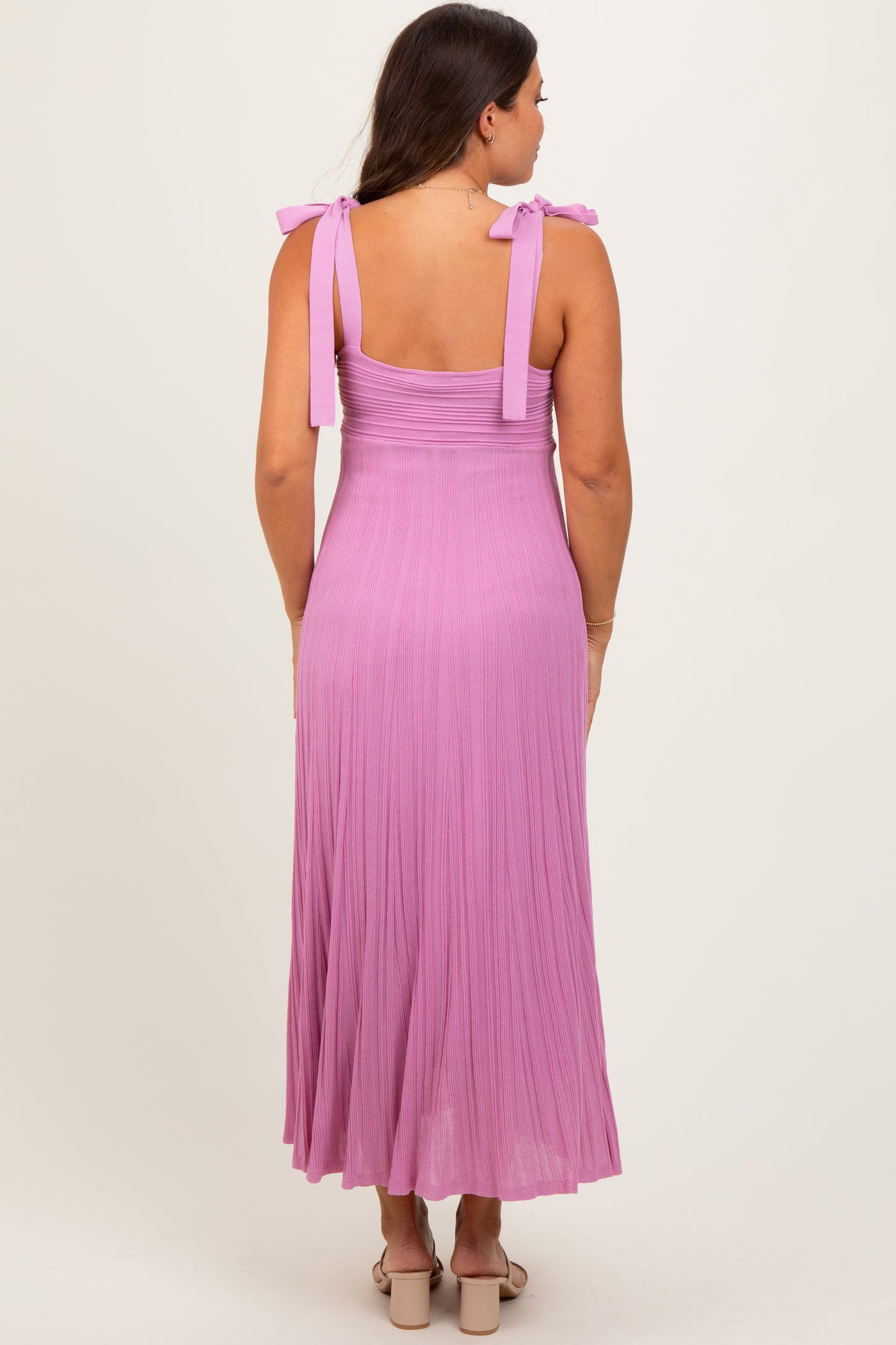 woman wearing a light purple maternity dress with tie straps and a flowing skirt, showing her back