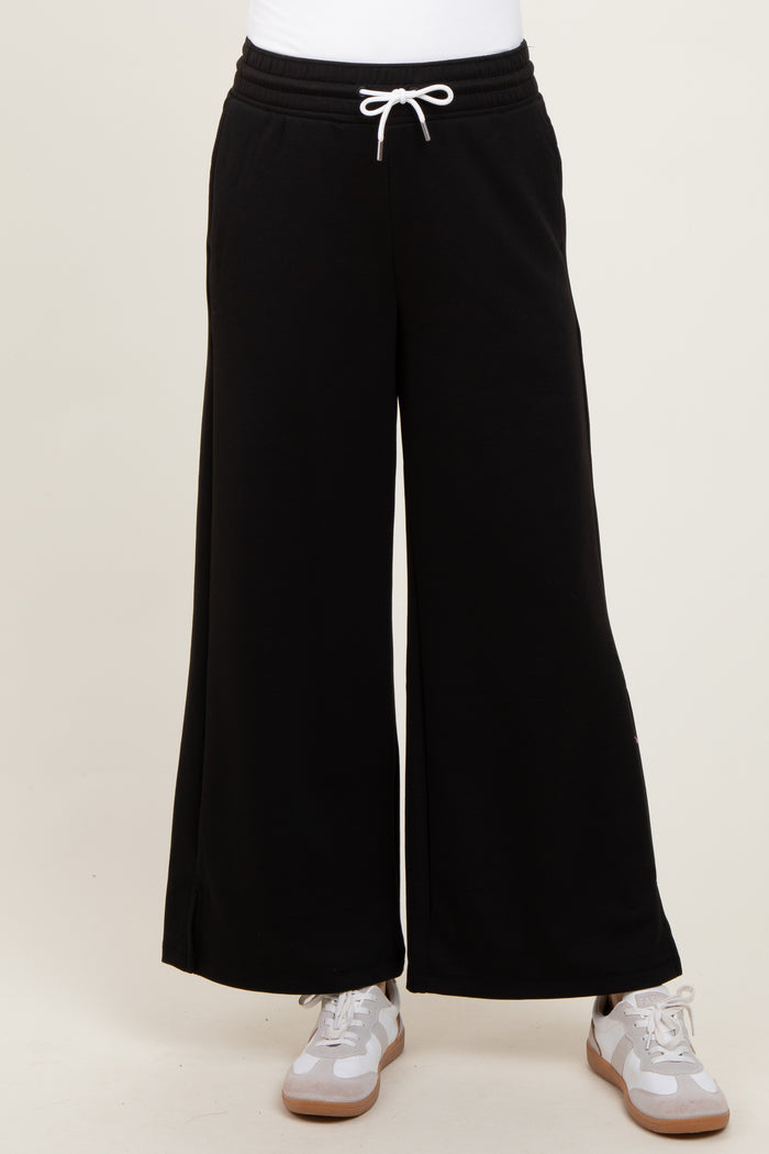 black wide-leg sweatpants with drawstring waistband styled with a white top and gray sneakers