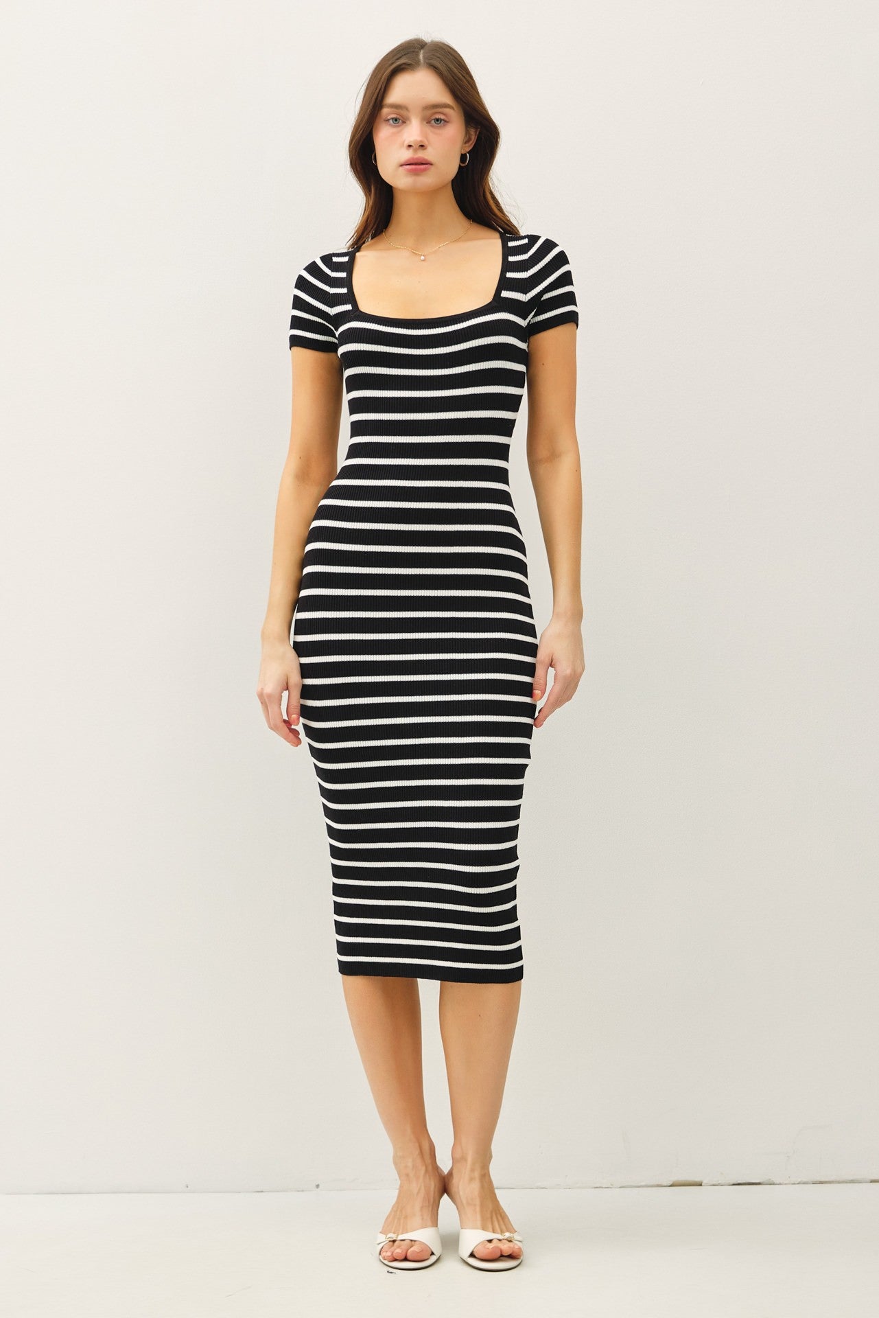 woman wearing a black and white striped short sleeve bodycon dress with a square neckline