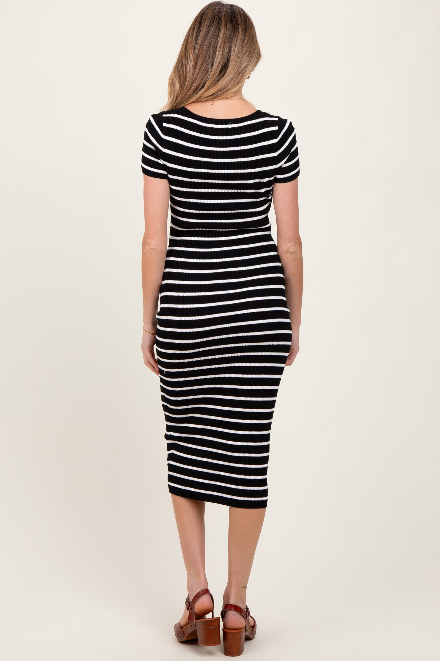 woman wearing a black and white striped maternity dress with a fitted silhouette and short sleeves