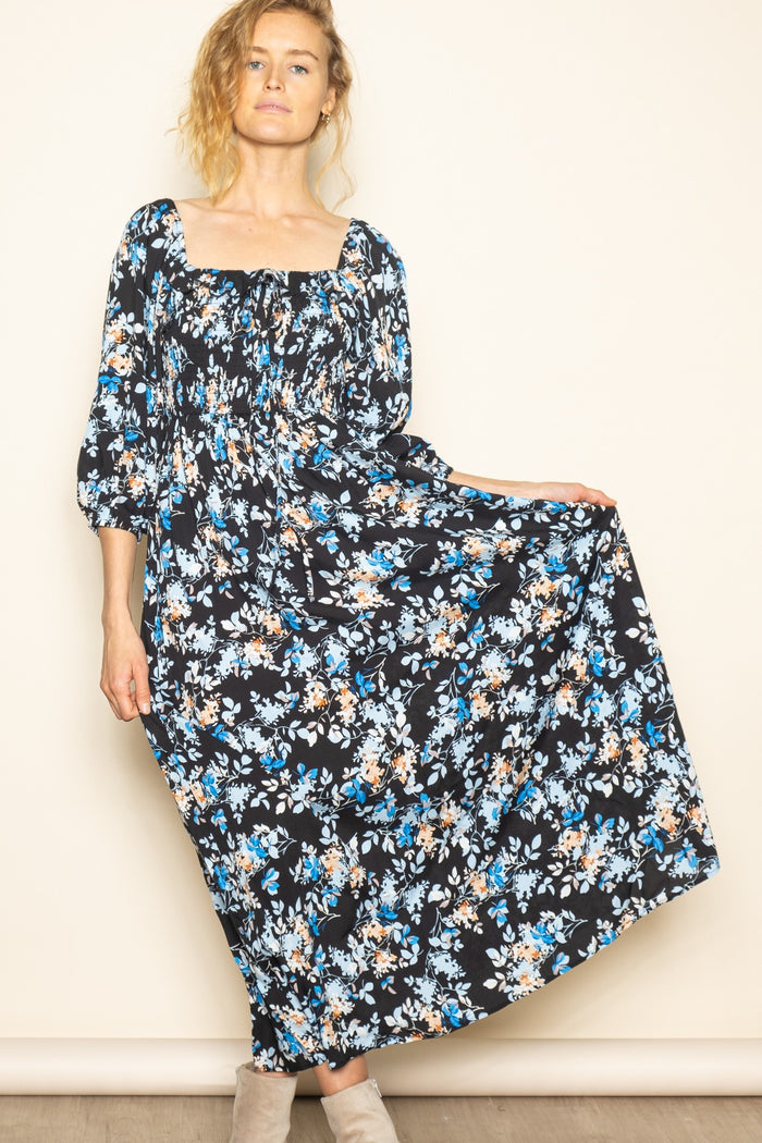 woman wearing a black floral maxi dress with a square neckline and puff sleeves
