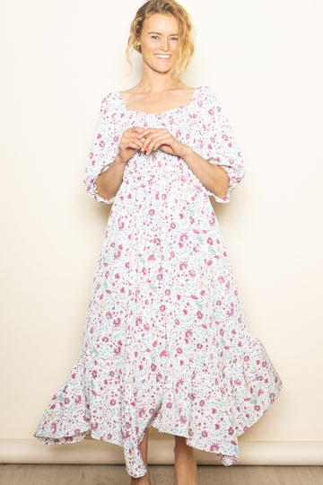 woman wearing a white floral maxi dress with a square neckline and three-quarter sleeves