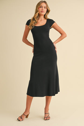 woman wearing a black fitted midi dress with cap sleeves and a flared hem, posing against a neutral background