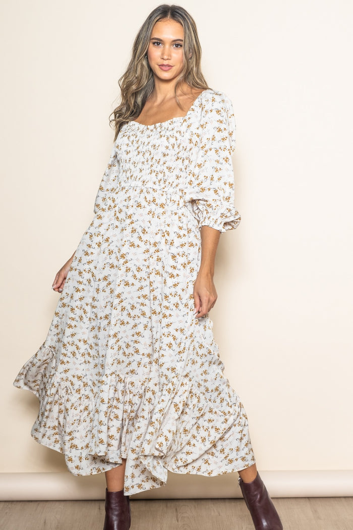 woman wearing a white floral midi dress with puff sleeves and a smocked bodice, posing against a neutral background