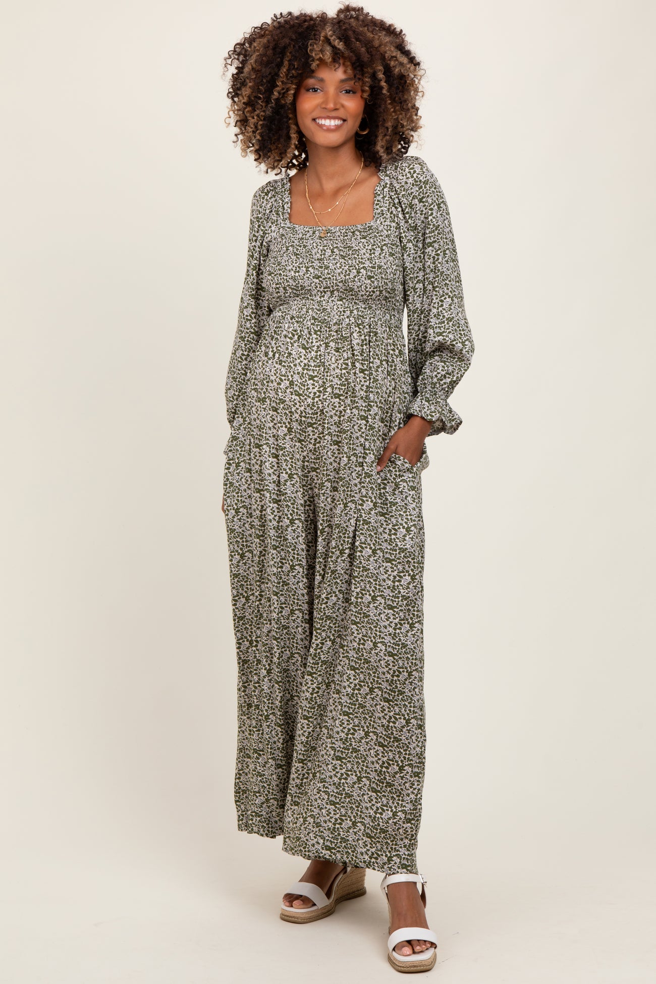 woman wearing a green floral maternity maxi dress featuring a square neckline and long sleeves, with a visible baby bump