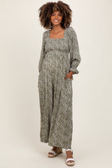 woman wearing a green floral maternity maxi dress featuring a square neckline and long sleeves, with a visible baby bump