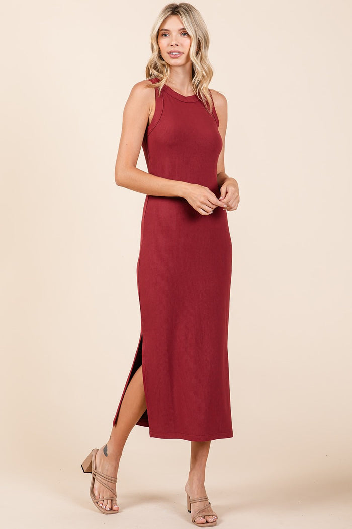 woman wearing a burgundy sleeveless maxi dress with side slits and standing in a relaxed pose