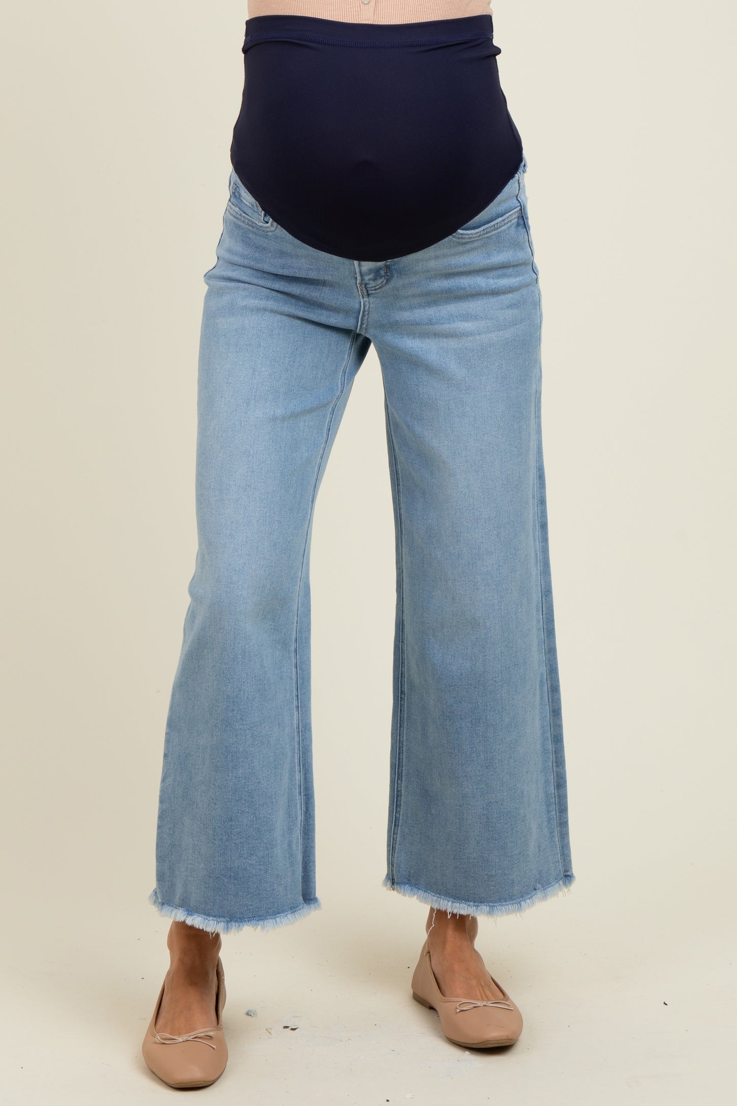 woman wearing light blue maternity wide-leg jeans with a dark blue panel, showing her baby bump