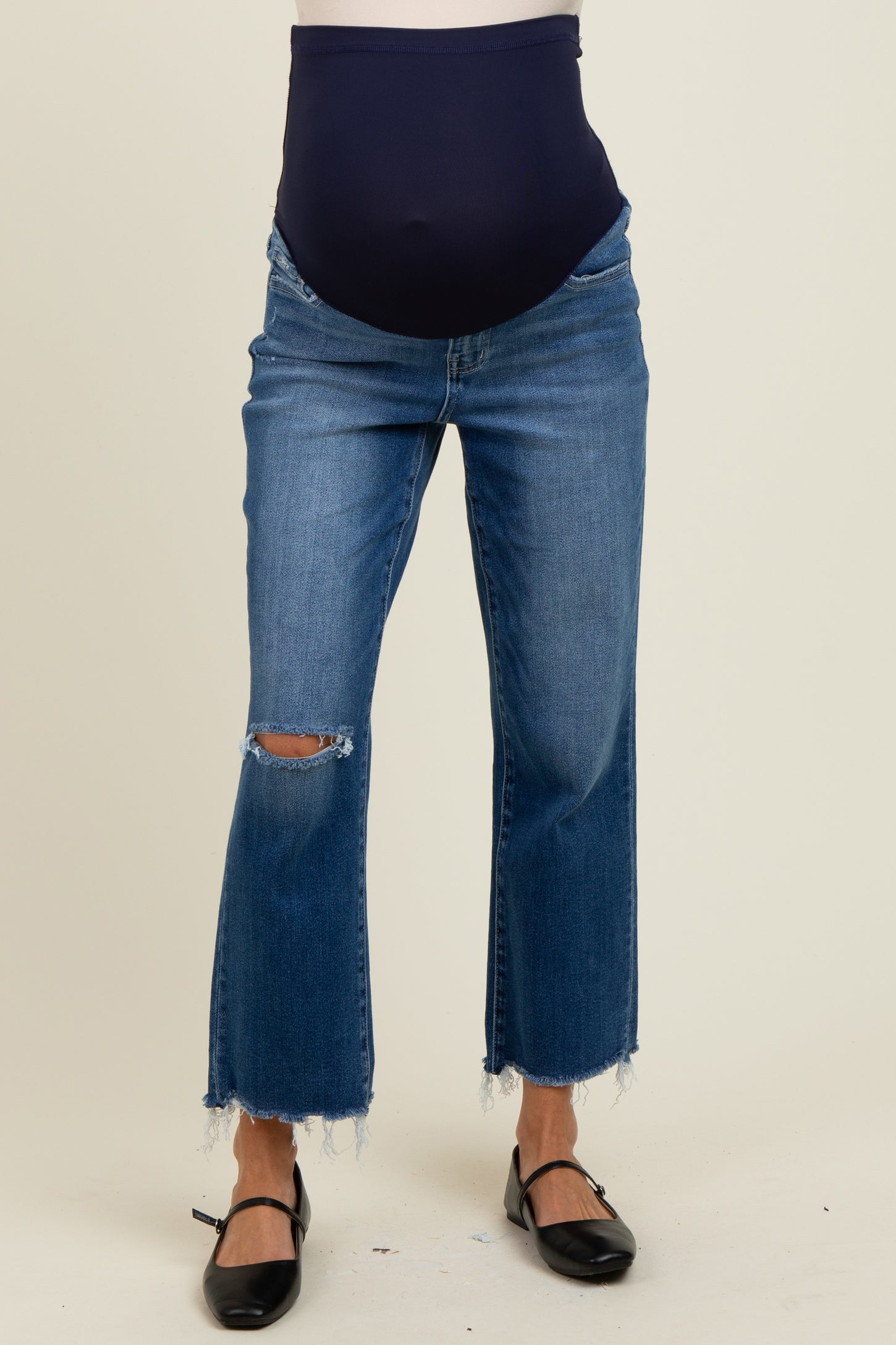 maternity wear featuring distressed blue jeans with a dark blue over-the-bump waistband, model displaying baby bump