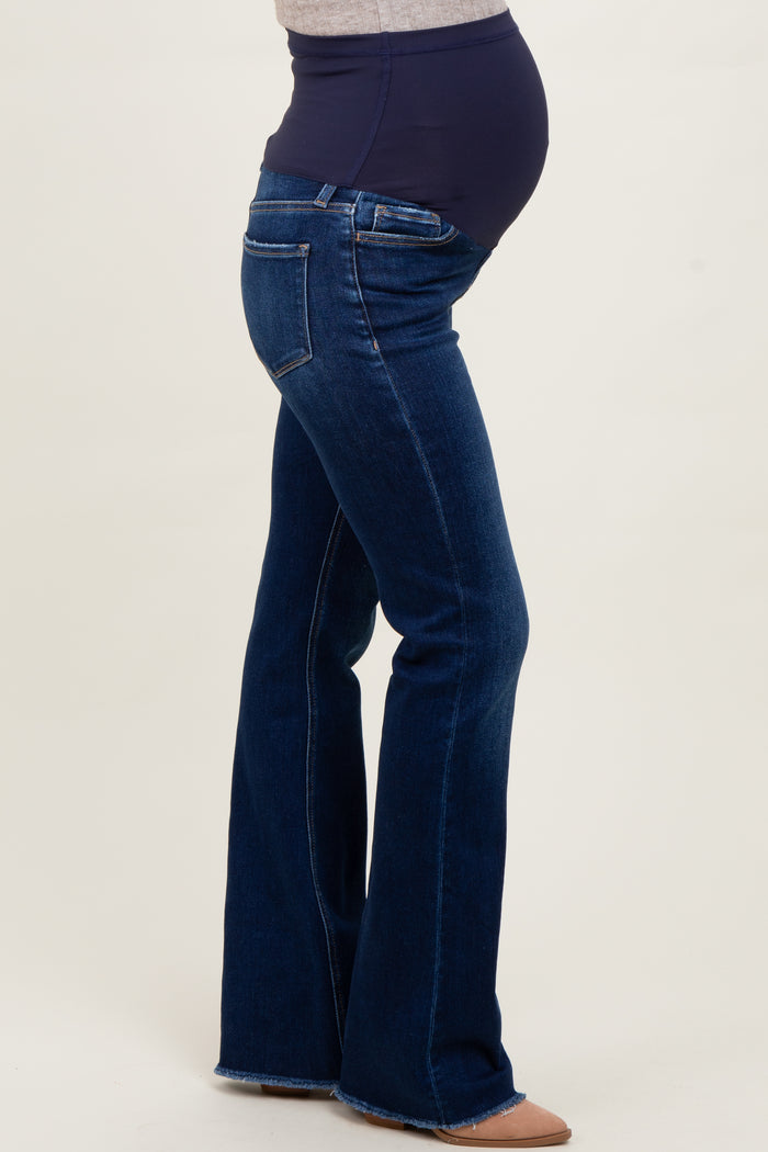woman wearing dark blue maternity flared jeans featuring a supportive waistband and showing her baby bump