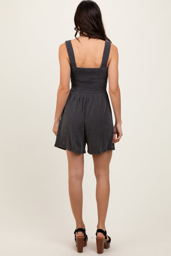 woman wearing a black and white striped smocked romper with a fitted bodice and flared shorts, viewed from the back