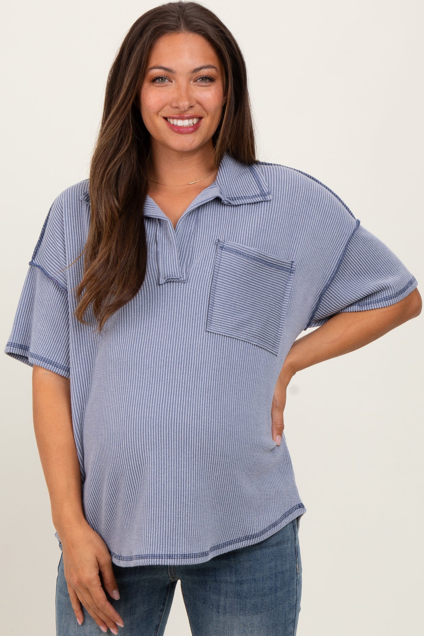 woman wearing a striped blue maternity polo shirt with a front pocket and a visible baby bump
