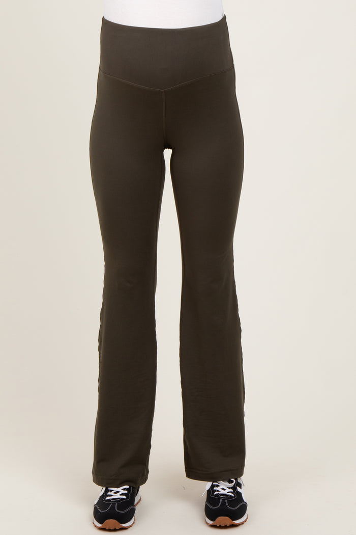 woman wearing dark green maternity active pants with a high waistband and a flared leg, paired with black sneakers