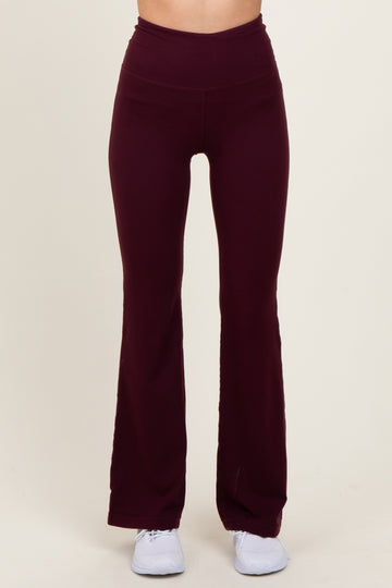 woman wearing burgundy flared workout leggings with a high waistband and paired with white athletic shoes