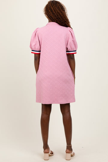 woman wearing a pink short-sleeve puffed dress with a textured pattern and contrast stripes on the sleeves