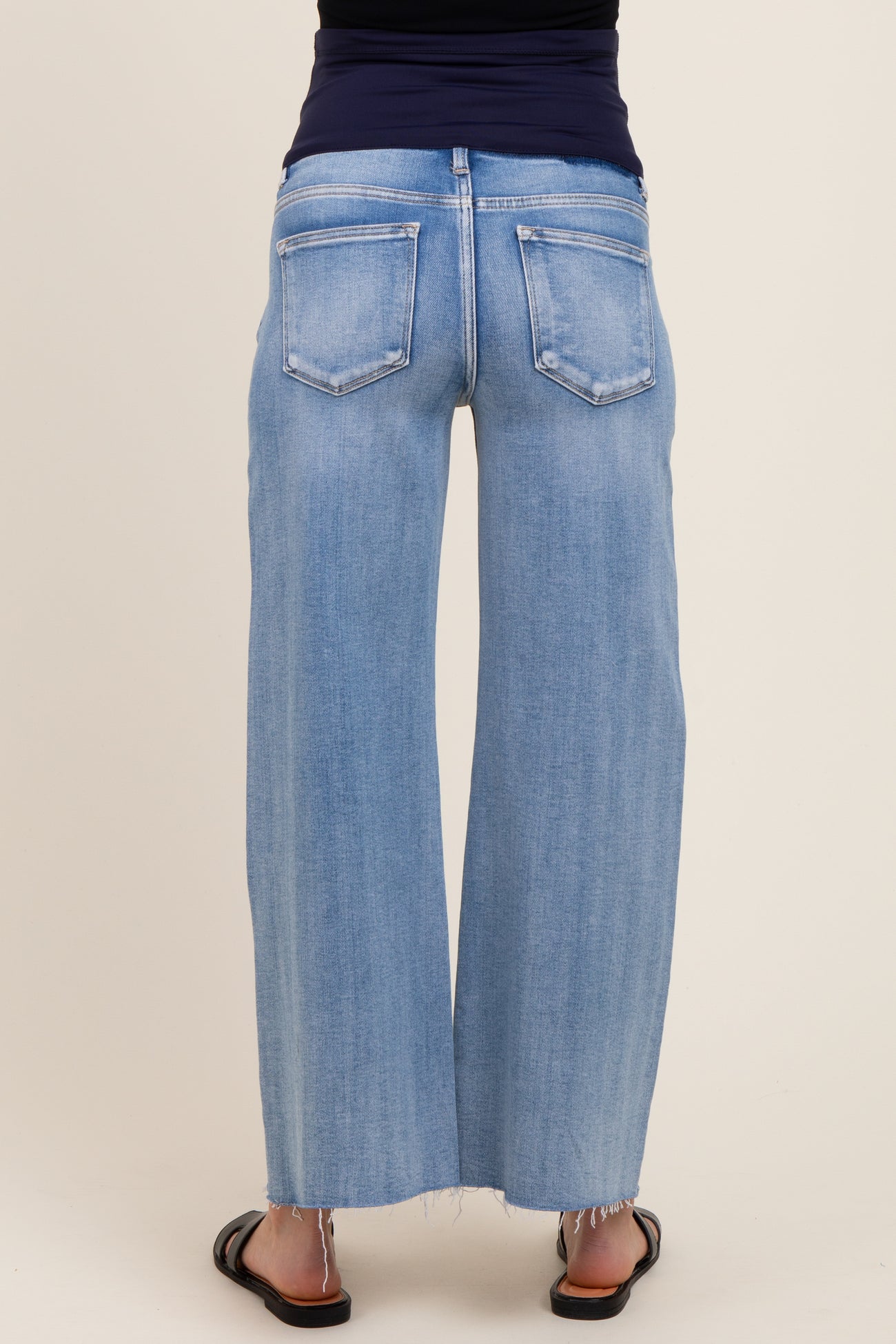 woman wearing light blue wide-leg maternity jeans with a frayed hem and back pockets