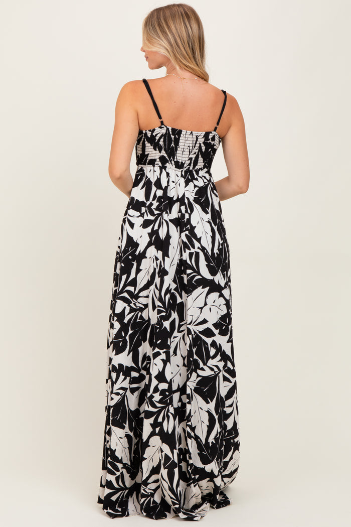 woman standing in a back view of a black and white floral maxi dress with spaghetti straps and a smocked bodice