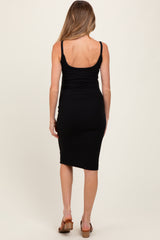 woman wearing a black ribbed maternity dress with adjustable straps, showing a fitted silhouette from the back