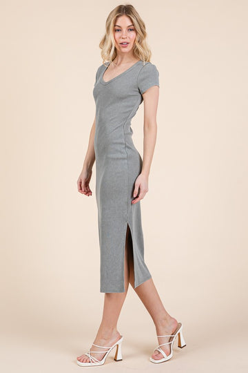 woman wearing a fitted gray midi dress with short sleeves and a side slit, paired with white heeled sandals