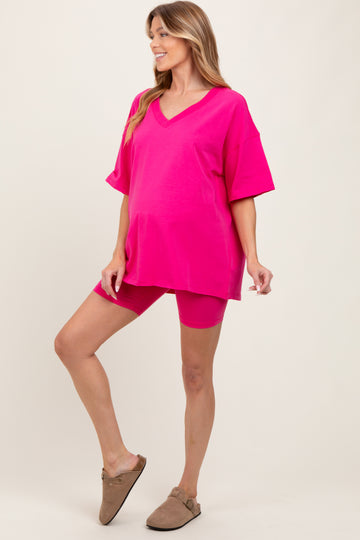 woman wearing a bright pink maternity short sleeve top and matching shorts, showing her baby bump