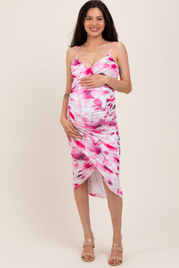 woman wearing a floral pink maternity dress, holding her baby bump with a ruched design and side slit