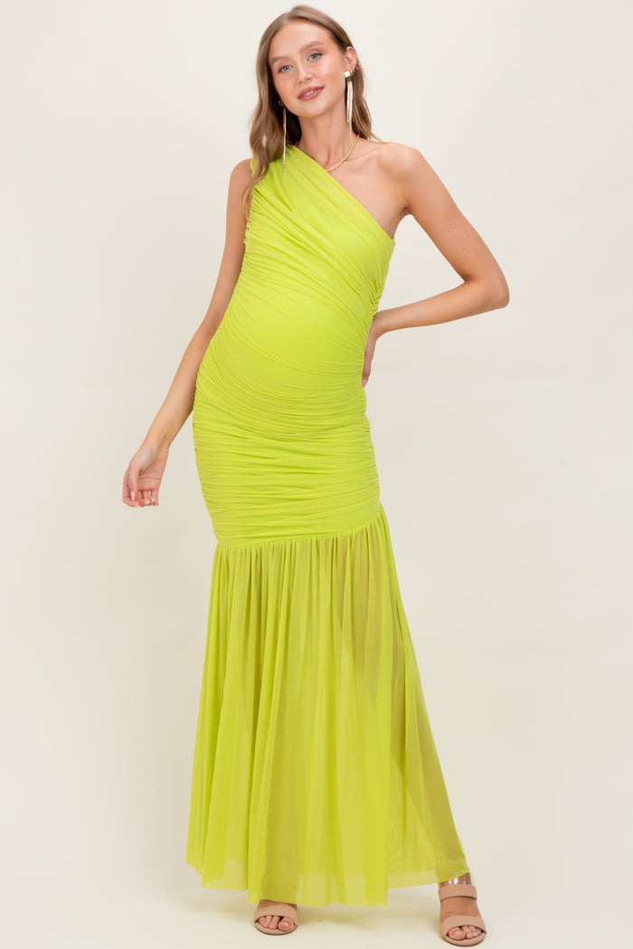 woman wearing a bright yellow one-shoulder maternity dress with ruched detailing and a flowing skirt, showcasing her baby bump