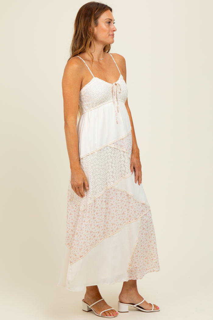 woman wearing a white floral maxi dress with spaghetti straps and tiered patterns, standing in profile