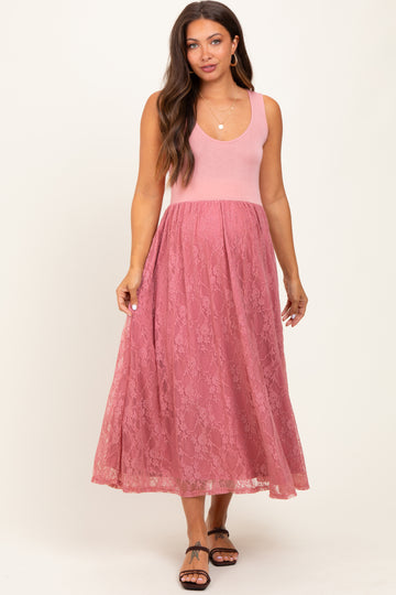 woman wearing a pink maternity dress with a fitted bodice and lace skirt, showing a baby bump