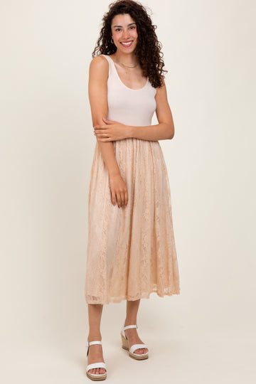 woman wearing a light pink tank top and a beige lace midi skirt with a flowy silhouette and standing in a natural pose