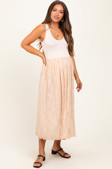 woman wearing a beige lace maternity dress with a fitted top and flowing skirt, showcasing her baby bump