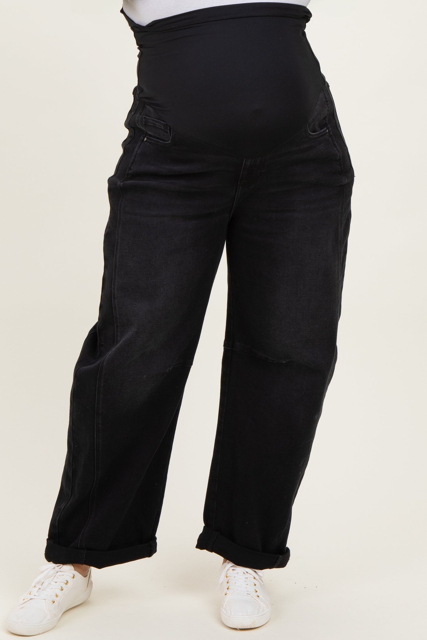 woman wearing black maternity plus wide-leg jeans with a stretchy waistband and rolled cuffs, white sneakers on feet