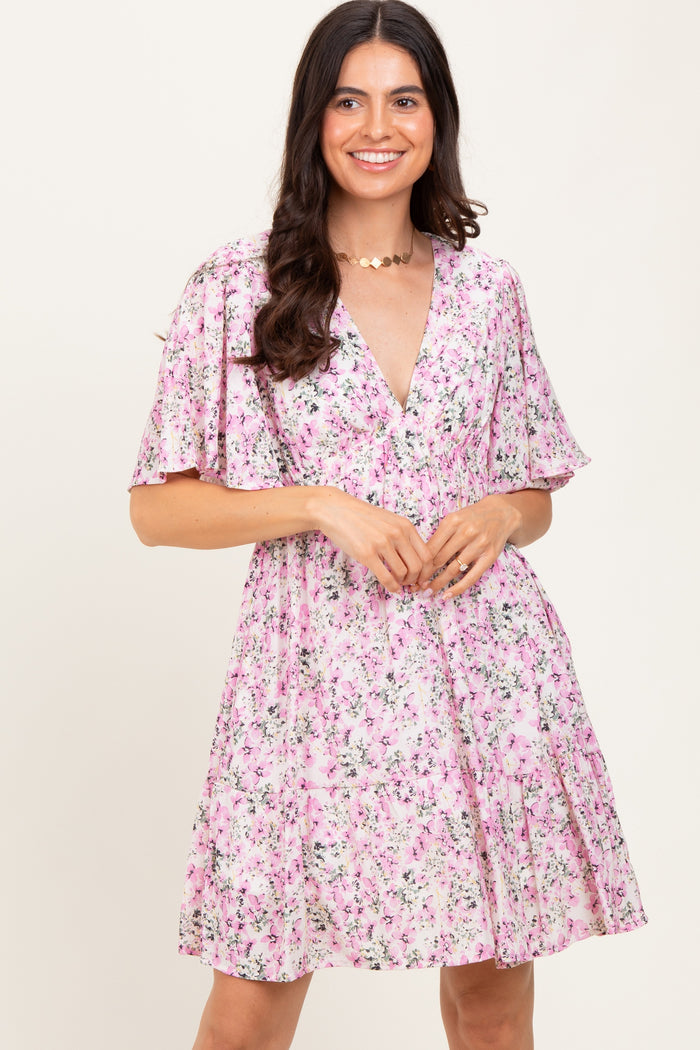 woman wearing a pink floral short sleeve dress with a deep v-neckline and a flared skirt