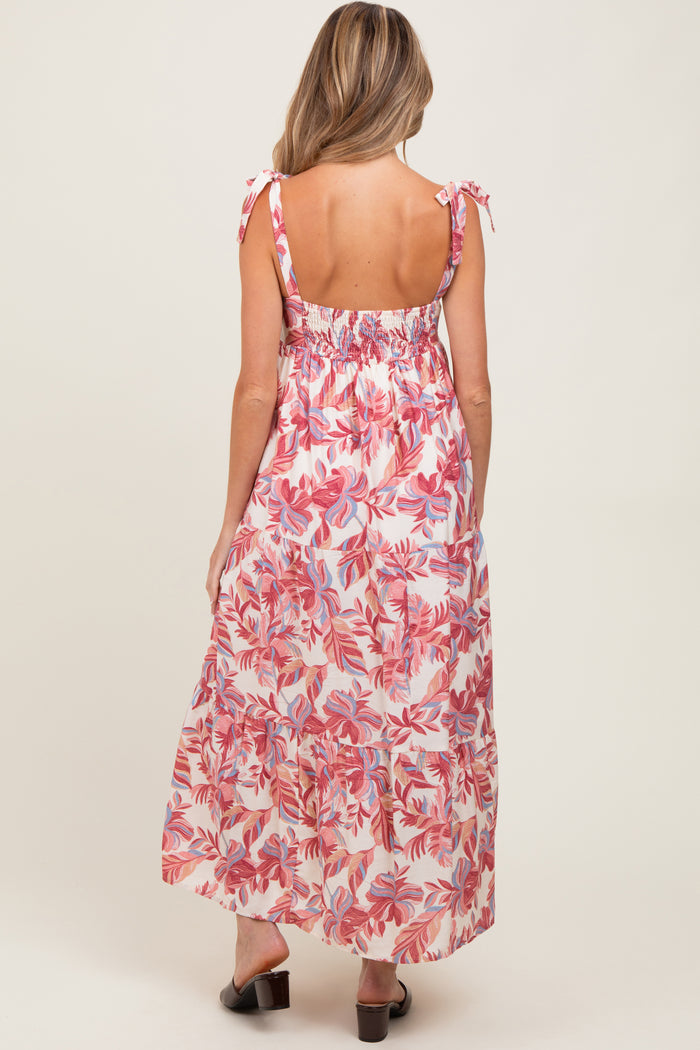 woman wearing a floral maternity maxi dress with tie straps, showcasing a relaxed fit and back smocking details