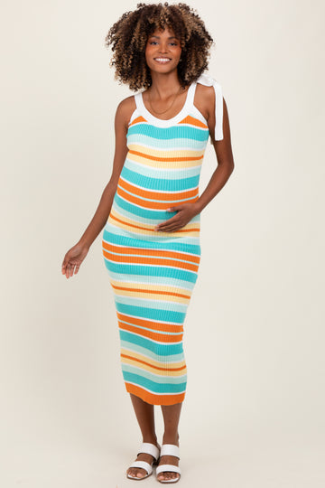 woman wearing a multicolored striped ribbed maternity dress with tied straps and holding her baby bump