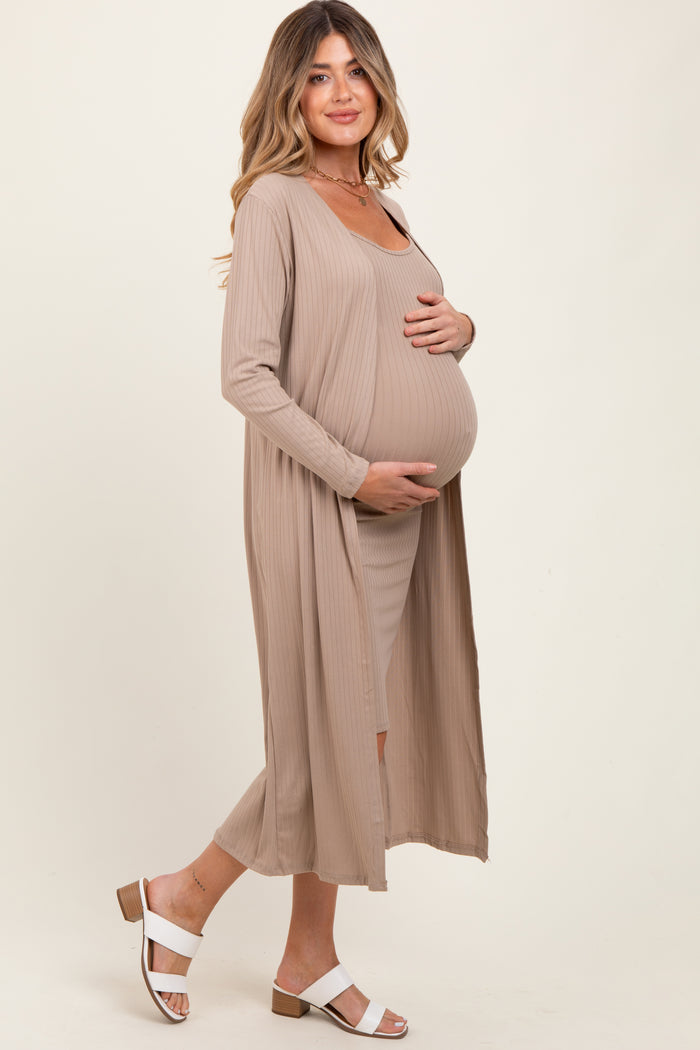 woman wearing a beige maternity dress with a long cardigan and holding her baby bump