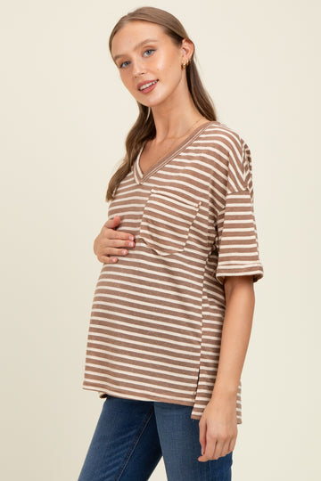 woman wearing a brown and beige striped maternity top and holding her baby bump