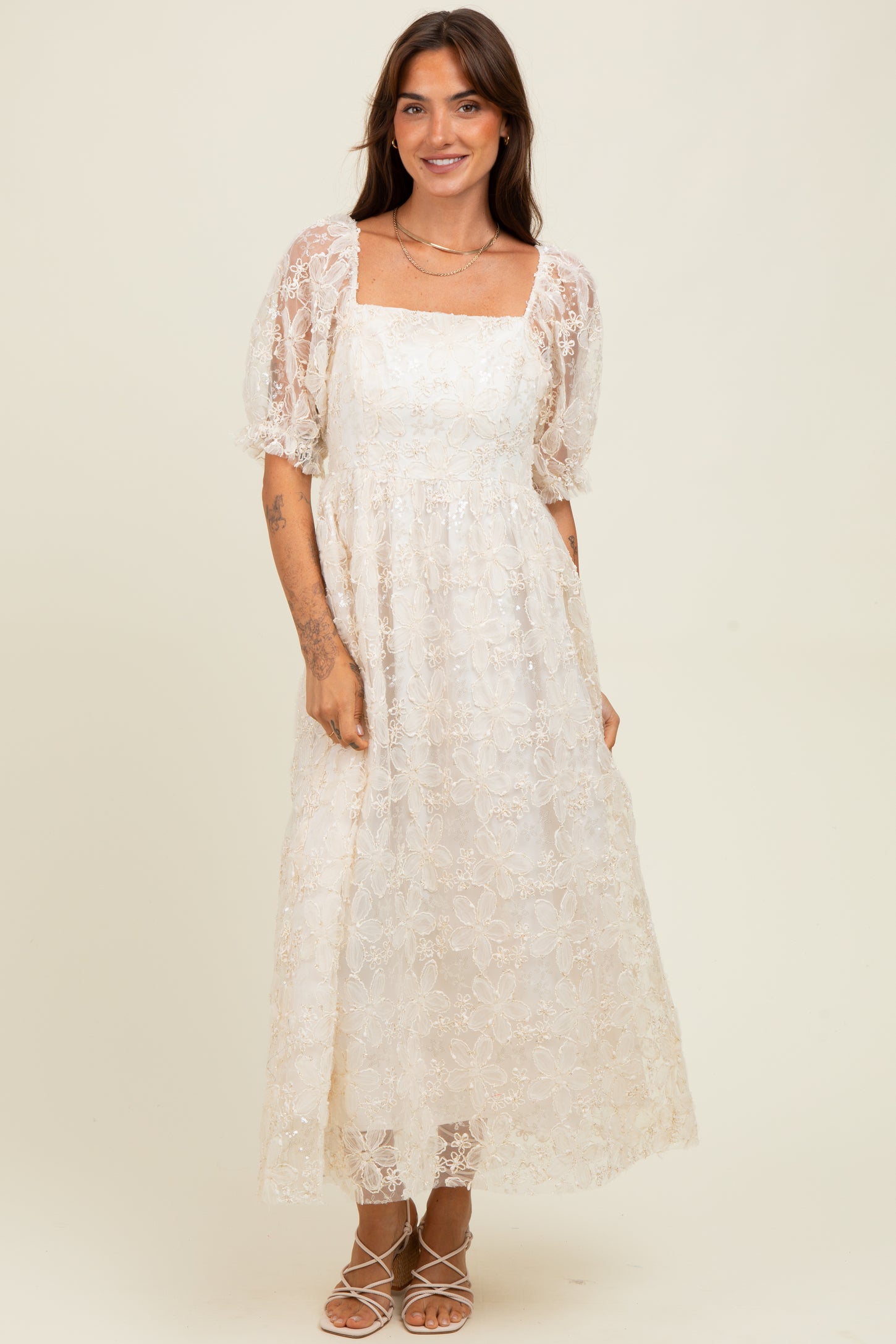 woman wearing a white floral lace maxi dress with puff sleeves and a square neckline