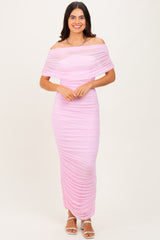 woman wearing a pink off-the-shoulder ruched maxi dress with a fitted silhouette