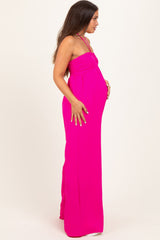 woman wearing a bright pink maternity maxi dress with a fitted bodice and flowing skirt, showing baby bump