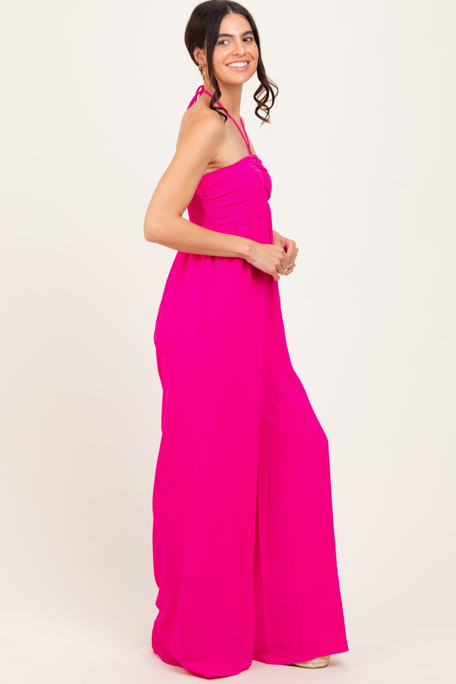 woman wearing a bright pink strapless jumpsuit with wide legs and a halter neck tie