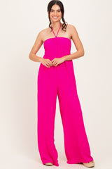 woman wearing a bright pink strapless jumpsuit with wide legs and tied halter neck