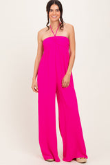 woman wearing a bright pink halter neck jumpsuit with a flowy wide leg design