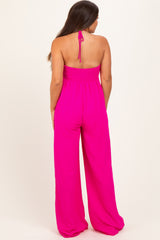 woman wearing a bright pink maternity jumpsuit with a smocked bodice and wide-leg pants, showing a baby bump from the back