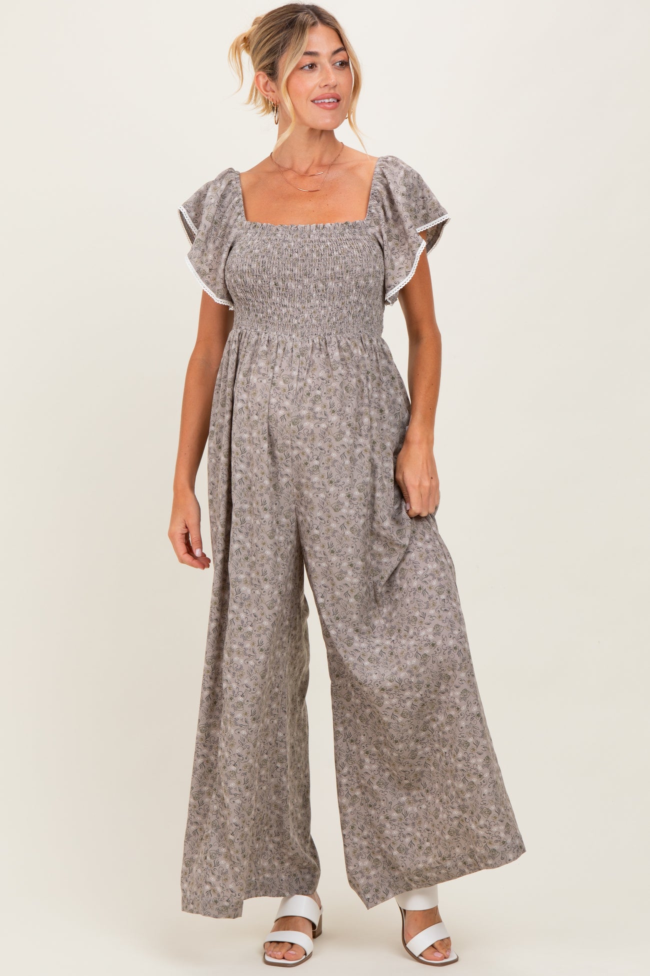 woman wearing a brown floral maternity jumpsuit with short ruffled sleeves and a smocked bodice